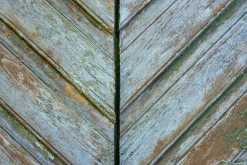 Close-up of weathered wooden planks with peeling paint forming a diagonal pattern, rustic vintage texture background.