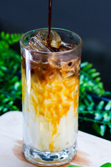 Close-up of iced caramel macchiato in a tall glass, layered with milk, caramel drizzle, and espresso over ice cubes.