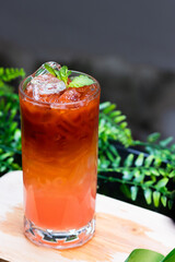 Refreshing iced Thai tea with gradient orange and pink layers, served in a tall glass with ice cubes and mint leaves.