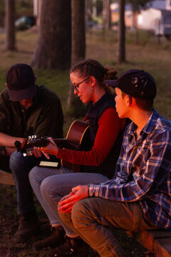 group of siblings sitting around singing together at campground at sunset