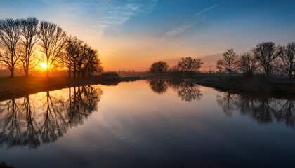Obraz premium tranquil river landscape at sunset with reflections and silhouetted trees on the water