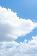 Bright blue sky with fluffy white cumulus clouds A vertical image showing a mostly clear sky