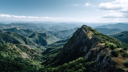 Naklejka premium A sweeping vista of a mountain range, showcasing a rugged peak, lush forests, and rolling hills under a vast blue sky.