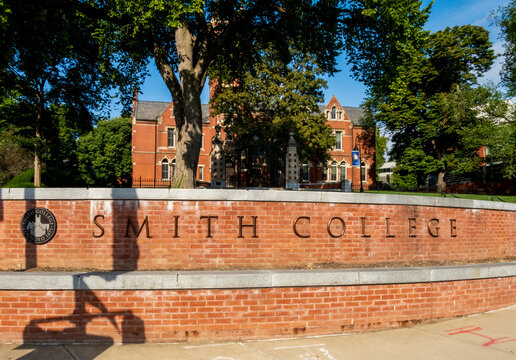 Northampton, MA - US - Aug 24, 2025 A brick wall sign with "SMITH COLLEGE" stands before a stately building amidst lush green trees under a bright sky, capturing a serene campus entrance.
