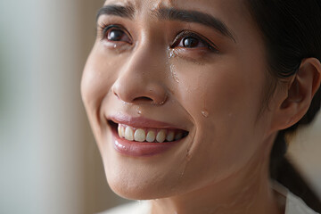 Close-up of a young woman crying tears of joy, bittersweet emotion, soft lighting.
