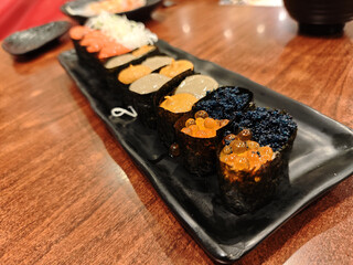 Delicious plate of Japanese food featuring gunkan sushi topped with fresh orange ikura and black tobiko roe ready to eat in restaurant
