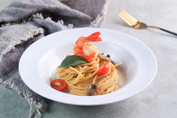 Spaghetti Aglio e Olio with shrimp and mushroom on white plate 
