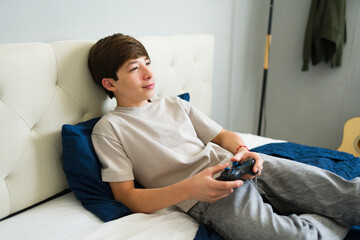 Teenager playing videogames relaxing on bed in bedroom © AntonioDiaz