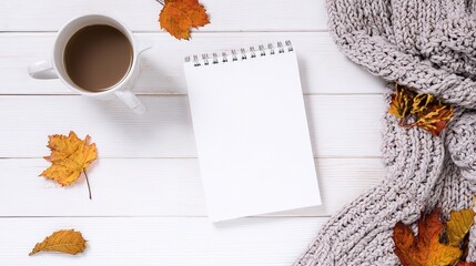 White blank notebook mockup on white wooden table with autumn leaves, coffee cup and knitted blanket, flat lay top view with copy space for blog design, social media content