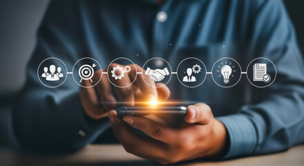 Business professional using a smartphone with digital icons representing business strategy, teamwork, goals, innovation, partnership, and success, illustrating modern corporate operations