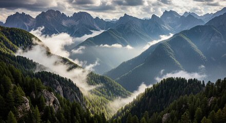 Dramatic alpine landscape with jagged mountain peaks shrouded in clouds and mist. The view overlooks a steep, forested valley, with the sun's rays breaking through the clouds
