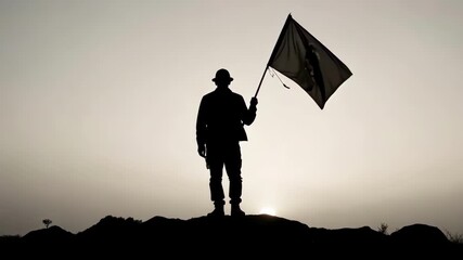 Silhouette of a determined person holding a flag aloft on a hilltop at sunset.
