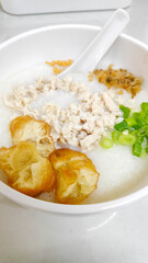 A delicious bowl of rice porridge topped with savory minced chicken, spring onions and pickled radish.