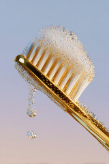 Gold-plated toothbrush with bubbly soap. Symbolizing luxury and dental care. Close-up, detail, shining.
