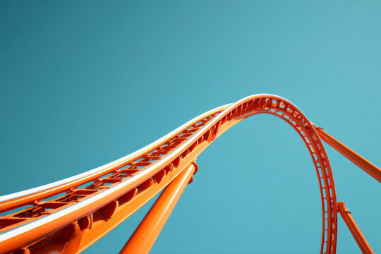 Orange rollercoaster track against a bright blue sky, curving and reaching upward, promising thrill and adventure