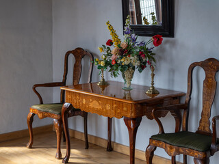 Antique table with two chairs and a magnificent floral arrangement placed on the tabletop, creating an elegant vintage atmosphere.