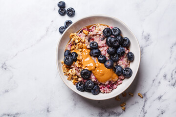 Oatmeal with blueberries and peanut butter, white background.