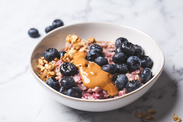 Oatmeal with blueberries and peanut butter, white background.