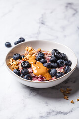 Oatmeal with blueberries and peanut butter, white background.
