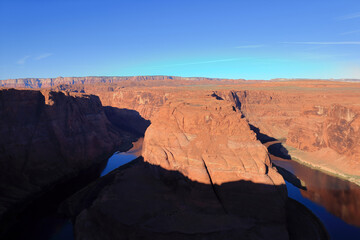 The Grand Canyon is the Colorado River. Mountains are visible behind. The photo was taken near the city of Page