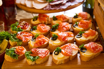 Delicious spread of gourmet bruschetta topped with fresh salmon and garnished with greens at a vibrant gathering
