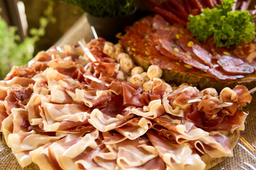 Gourmet charcuterie spread featuring assorted cured meats and fresh greens on a rustic wooden platter