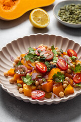 Autumn warm chickpea and roasted pumpkin salad with fresh cherry tomatoes and herbs. Vegan meals