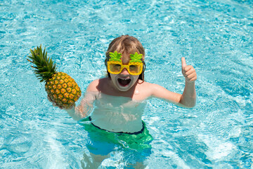 Happy child playing in swimming pool. Summer kids vacation. Little kid boy relaxing in a pool having fun during summer vacation.