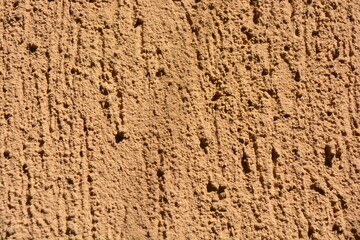 Construction, repair work, lining, covering walls with the latest materials. Brown wide background with voluminous granules, drops, textured sand on the street wall.
