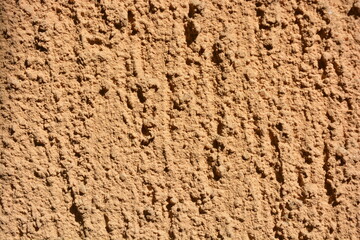 Construction, repair work, lining, covering walls with the latest materials. Brown wide background with voluminous granules, drops, textured sand on the street wall.