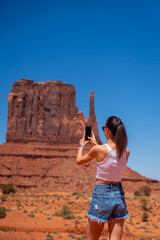 Young Woman Photographing Monument Valley Formations with Smartphone