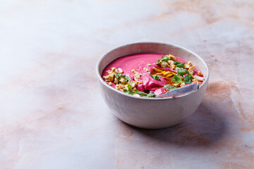 Pink beetroot hummus with nuts, oil and herbs.