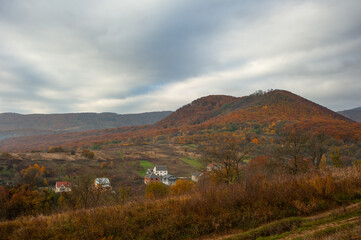 Red autumn has arrived with a cloudy sky over a village in a mountainous area