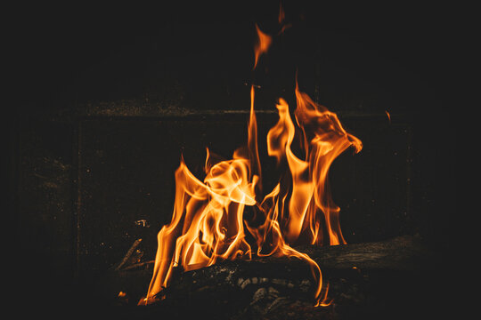 Bright orange flames rising from a wood vine barbecue fire, glowing and crackling with natural warmth