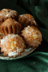 Delicious homemade muffins sprinkled with powdered sugar on green velvet background