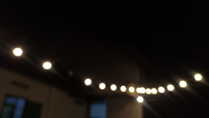 Blurry photo of glowing string lights at night, creating a soft bokeh effect and cozy atmosphere....