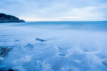 Storm in Gelendzhik on long exposure. Waves in form of fog run into beach of Gelendzhik. Twilight, sunset.