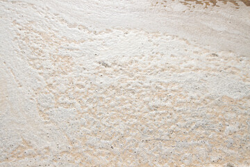 Close-up of crystallized salt formations and foam on water surface. Close-up of white beige salt crust texture with natural wave-like patterns on surface.