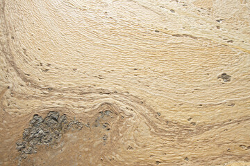 Close-up of crystallized salt formations and foam on water surface. Close-up of white beige salt crust texture with natural wave-like patterns on surface.