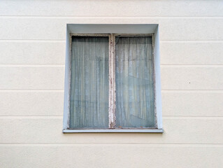 Weathered wooden window shutters with metal hardware mounted on plain white building facade. High quality photograph