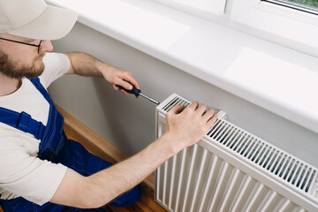 Home heating maintenance by a technician installing a radiator in a living space