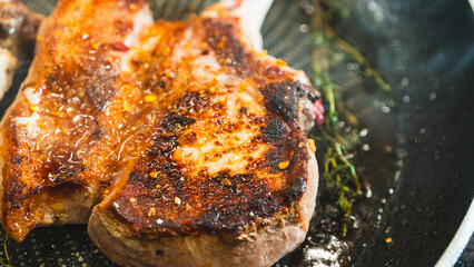 Juicy bone-in pork chops sizzling in a pan with golden fried garlic and fresh thyme sprigs. Beautifully cooked and presented for food content.