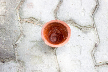 A small terracotta pot with rough texture sits on a patterned concrete surface