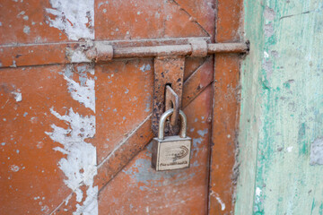 Rusty padlock securing an old metal door with a sliding bolt