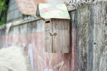 Rustic wooden mailbox with camouflage lid attached to a wall