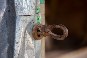 Closeup of a rusty metal eye bolt attached to a weathered post