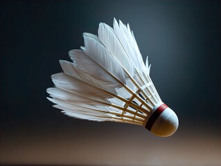 Close-up Studio Shot of a White Feathered Badminton Shuttlecock with a Red Band, Elegantly Suspended Against a Dark, Atmospheric Background