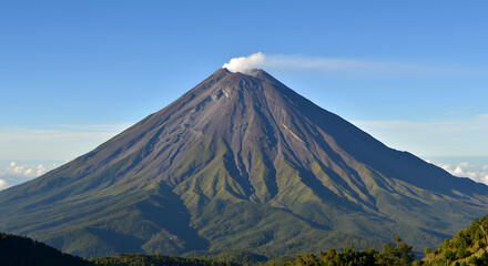 Fototapeta premium Scenic view of a majestic active stratovolcano emitting a plume of smoke against a clear blue sky on a sunny day
