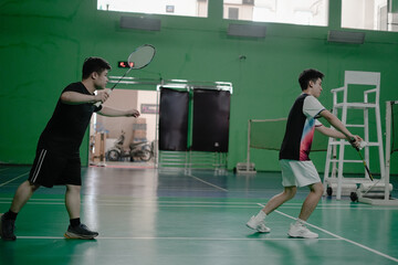 two players competing in a badminton match on an indoor court