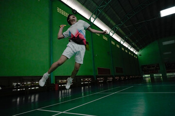player performing a smash hit during a badminton match on indoor court